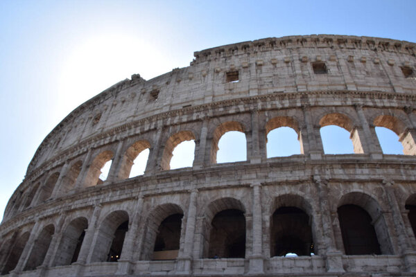 The sun shining behind the shell of the colosseum in Rome
