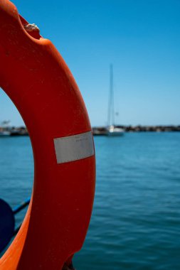 Vilchada, Greece - July 18 2019:   A lifebelt on the dock side with a yacht in the distance behind it