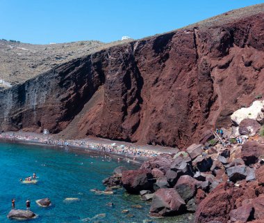 Akrotiri, Yunanistan - 19 Temmuz 2019: Ege Denizi 'nin mavi suları Akrotiri' nin Kızıl Sahili 'ndeki kızıl kayalıklarla keskin bir tezat oluşturuyor