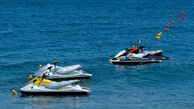 Perissa, Greece - July 18 2019:   Four jetskis awaiting tourists are anchored in the Aegean sea just off the Perissa Beach