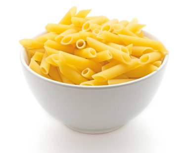 Penne rigate beyaz arka plan kuru pişmemiş makarna parçası üzerinde izole porselen kase