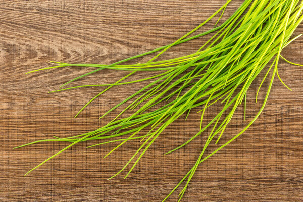 Fresh chives table top isolated on brown wood background grass slender leave