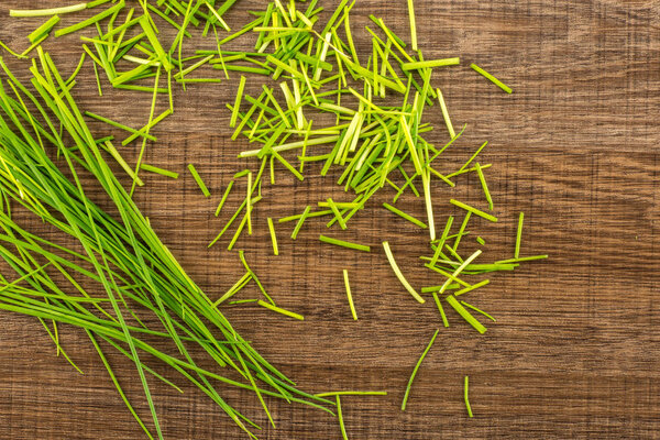 Fresh chives table top isolated on brown wood background grass-like leaves fines herbe