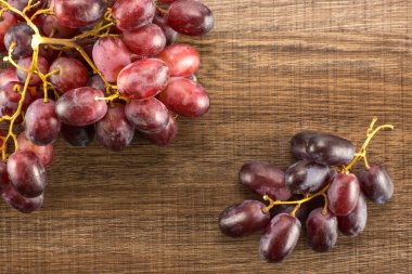 Kahverengi ahşap arka plan koyu pembe berrie izole iki kırmızı küre üzüm kümeleri masa üstü