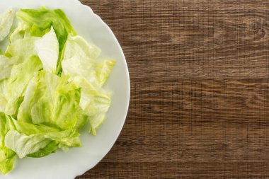 Göbek salatayı taze yırtık salata üzerinde kahverengi ahşap adam izole bir beyaz tabak masa üstü yaprak