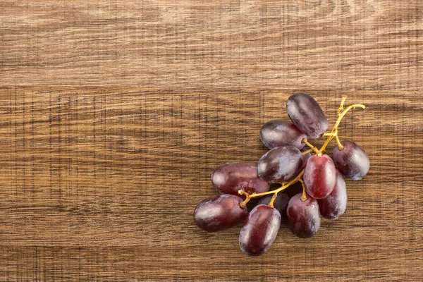 Red globe grapes one cluster table top isolated on brown wood background shiny deep pink berrie