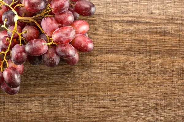 Red globe grape cluster table top isolated on brown wood background dark pink berrie