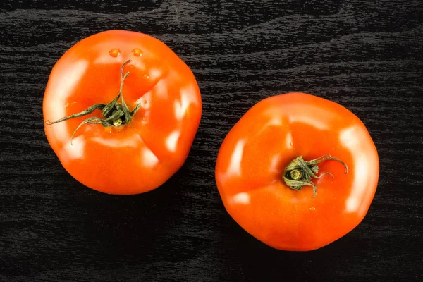 两个红色的西红柿被隔离在黑色的木材背景顶部竞争 — 图库照片