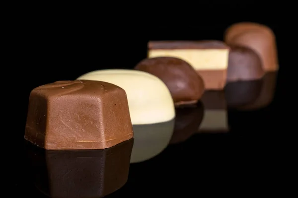 Шоколадные конфеты, изолированные на черном стекле — стоковое фото