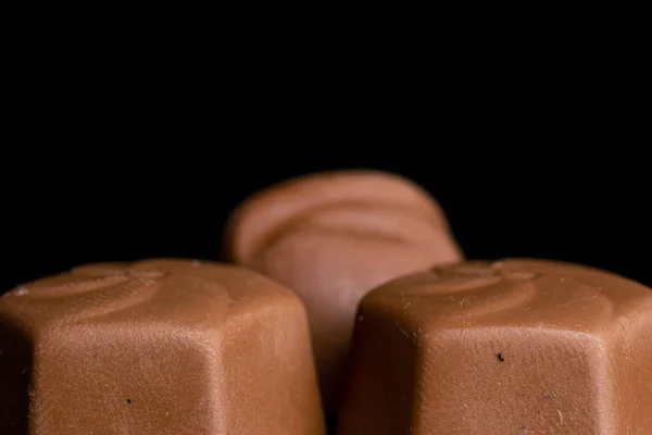 Chocolade praline snoepjes geïsoleerd op zwart glas — Stockfoto
