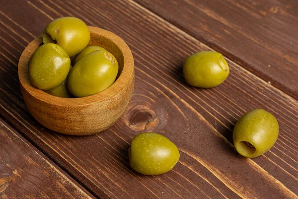 Olive verdi snocciolate su legno marrone — Foto Stock