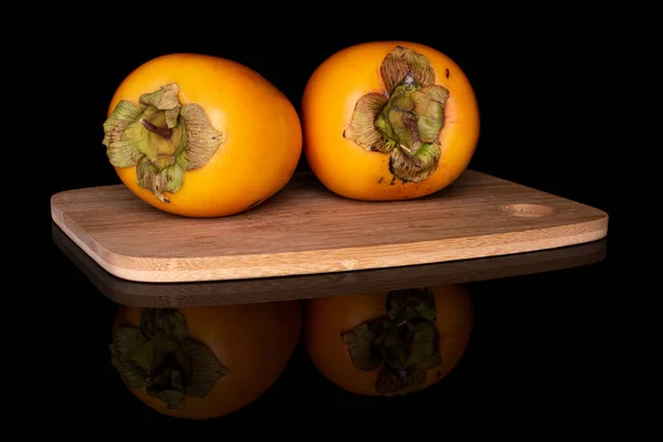 Sweet orange persimmon isolated on black glass — Stock Photo, Image