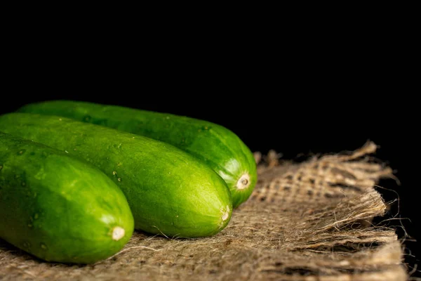 Fresh green baby cucumber isolated on black glass — Stock Photo, Image
