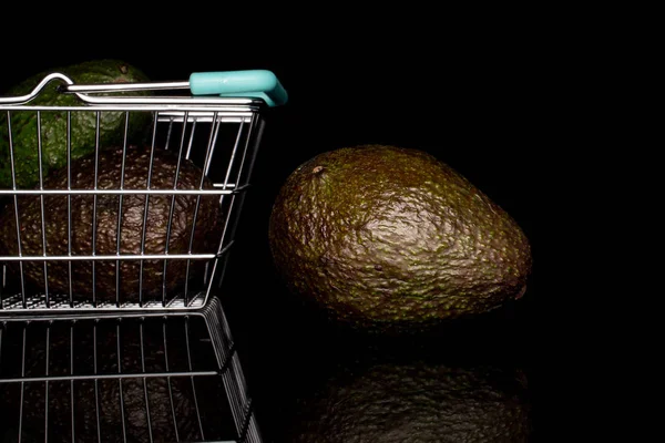 Свежий зеленый авокадо изолирован на черном стекле — стоковое фото