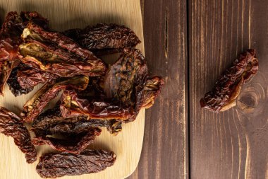 Kahverengi tahtada güneşte kurutulmuş domates.