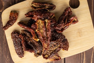 Kahverengi tahtada güneşte kurutulmuş domates.