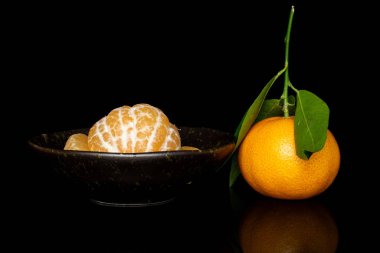 Taze turuncu mandalina siyah camda izole edilmiş.