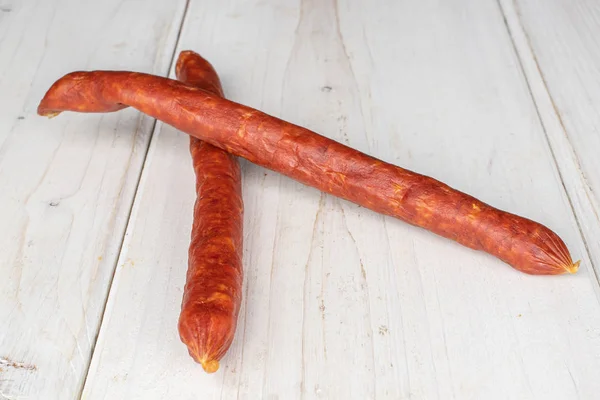 Копченая острая колбаса на серой древесине — стоковое фото