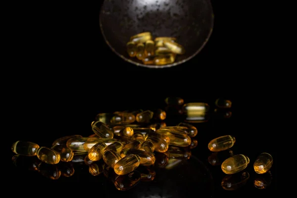 Złoty olej rybny izolowany na szkle czarnym — Zdjęcie stockowe