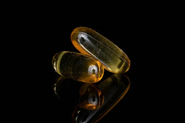 Aceite de pescado dorado aislado en vidrio negro — Foto de Stock