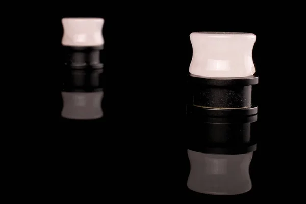 Stylischer Ohrstöpsel isoliert auf schwarzem Glas — Stockfoto