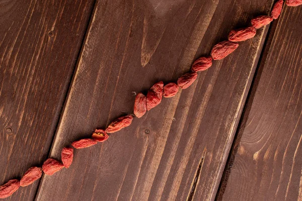 Red dried goji on brown wood — Stockfoto