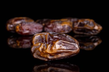 Dry brown date fruit isolated on black glass