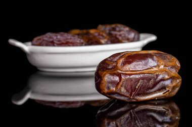 Dry brown date fruit isolated on black glass