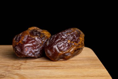 Dry brown date fruit isolated on black glass