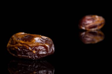 Dry brown date fruit isolated on black glass