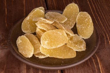 Kahverengi ahşap üzerinde seramik bardak altlığı olan kurutulmuş sarı ananas dilimleri.