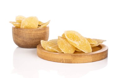 Bambu kasesinde beyaz arka planda izole edilmiş bambu altlığı üzerinde kurutulmuş sarı ananas dilimleri.