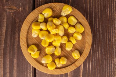 Kahverengi ahşap üzerinde bambu bardak altlığı üzerinde bir sürü konserve sarı mısır.