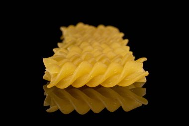 Bir sürü sarı fusilli makarna siyah camla izole edilmiş.