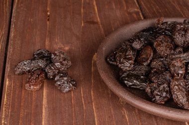 Kahverengi ahşap üzerinde seramik bardak altlığı olan kuru üzümlü kuru üzüm.