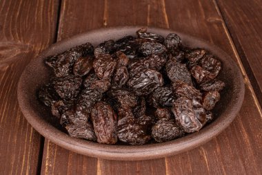 Kahverengi ahşap üzerinde seramik bardak altlığı olan kuru üzümlü kuru üzüm.