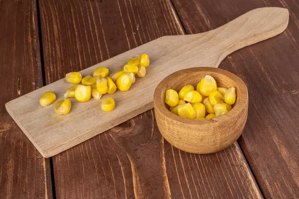 茶色の木に竹のボウルに木製のまな板に缶詰の黄色のトウモロコシの作品の多く — ストック写真