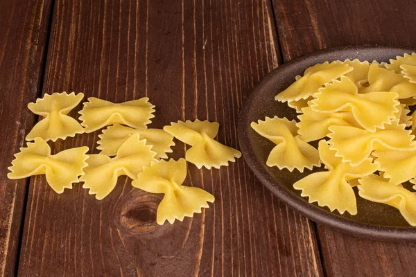 Mycket Hel Gul Pasta Farfalle Med Brun Keramik Underlägg Brunt — Stockfoto