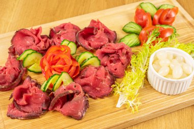 Ahşap kesme tahtasının üzerinde soğan turşusuyla dilimlenmiş güzel biftek.