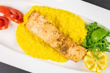 Gri taşın üzerinde beyaz dikdörtgen seramik tabakta patates püresi ile ızgara güzel somon balığı.