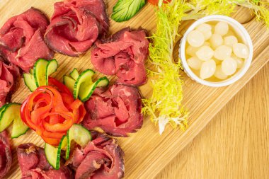 Güzel dilimlenmiş biftek ve ahşap kesim tahtasının üzerinde soğan turşusu.