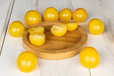 Sekiz tam dört yarımlık taze sarı domates grubu beyaz ahşap üzerinde bambu altlığı üzerinde.