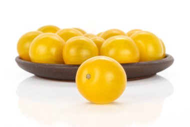 Bir sürü taze sarı domates ve beyaz arka planda izole edilmiş kahverengi seramik bardak altlığı.