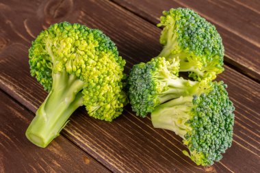 Kahverengi ahşap üzerinde dört taze brokoli grubu.