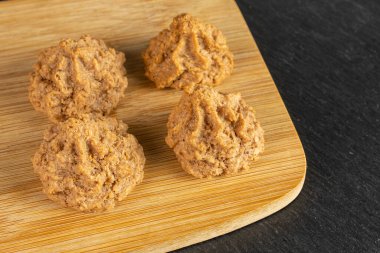 Dört kişilik bir grup ev yapımı kahverengi hindistan cevizli bisküvi. Gri taşın üzerinde bambu dilimleme tahtası ve çikolata.