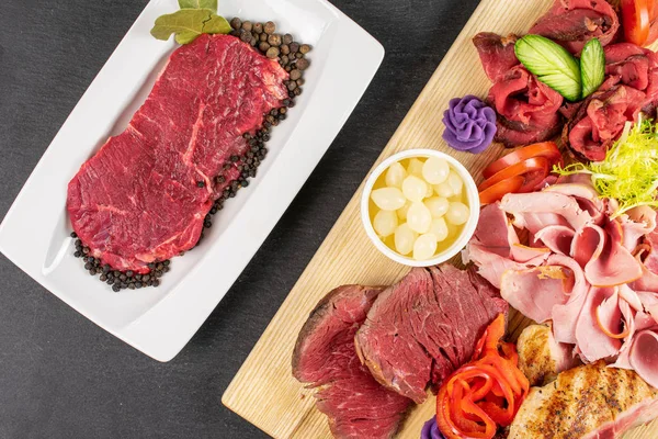 Beautiful meat board and raw beef sirloin with spices on white rectangular ceramic plate flatlay on grey stone