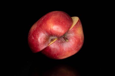 İki parça dilimlenmiş kırmızı elma. Siyah cam üzerinde izole edilmiş.