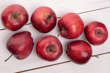 Beyaz ahşap üzerinde yedi tam kırmızı elma grubu.