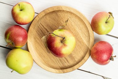 Tahta tabakta beyaz ahşap üzerinde altı tane taze elma grubu.