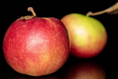 İki taze elma grubu, siyah cam üzerinde izole edilmiş.